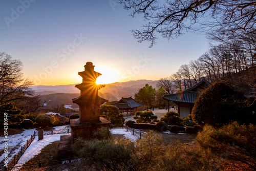 Yeongju-si, Gyeongsangbuk-do, South Korea - January 21, 2023: Sunset view of snow covered three-story stone pagoda and tile roof of Muryangsujeon Hall at Buseoksa Temple
 photo