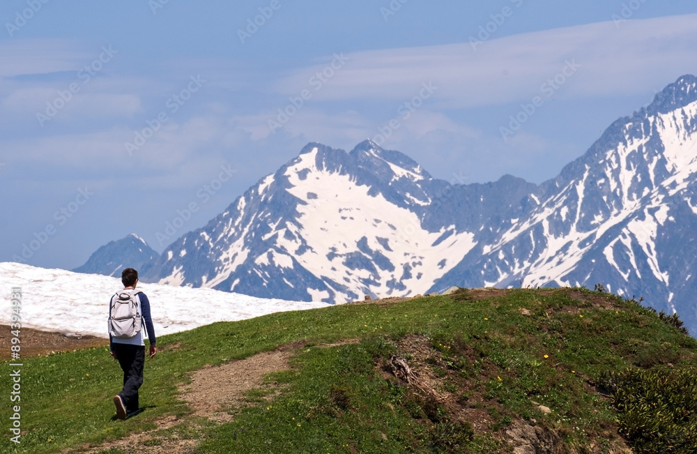 Man with backpack walks along hiking trail in mountainous area. Hiking concept. Man with backpack walks along hiking trail in mountainous area. Hiking concept.