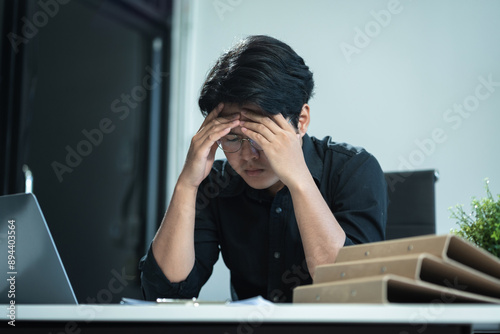 Young stressed Asian businessman working in the office. Businessman thinking too much work concept in the office.