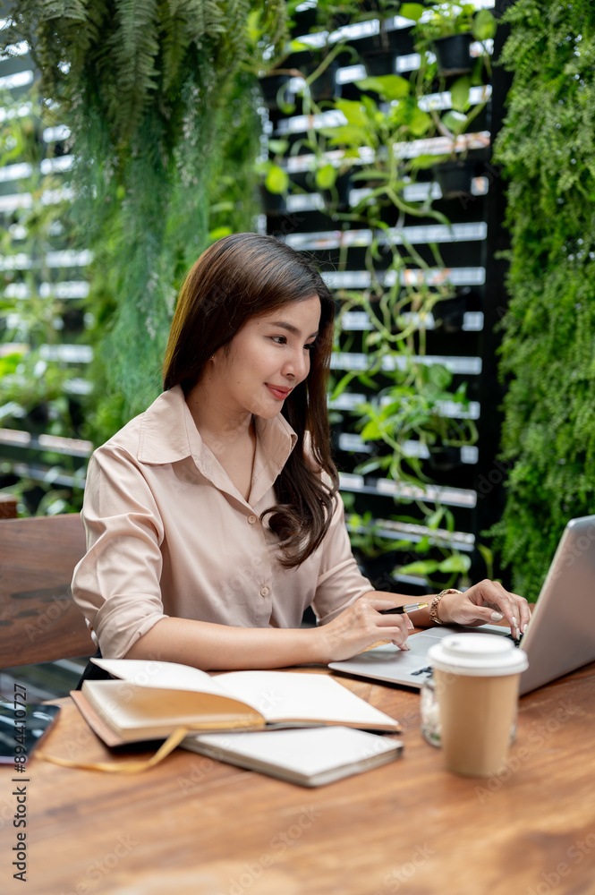 A beautiful Asian woman working remotely from a coffee shop, working on her laptop computer. A beautiful Asian woman working remotely from a coffee shop, working on her laptop computer.