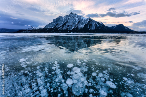 Natural bubbles frost on frozen Abraham Lake with rocky mountains in winter at Canada photo