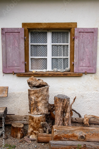 old wooden window in a swiss village surrounded by trunks of wood