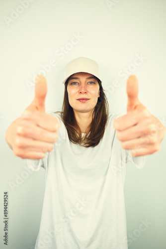 Obraz na płótnie Portrait of beautiful Caucasian young female model with blue eyes and white shirt showing thumbs up gesture, isolated on white background, copy space area w salonie