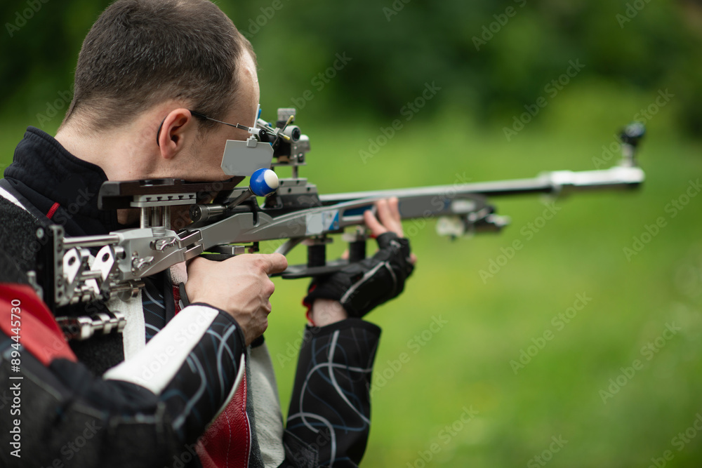 A skilled male athlete engages in free rifle training outdoors, demonstrating his expertise and precision in shooting, known for his dedication and focus in the open-air practice environment. A skilled male athlete engages in free rifle training outdoors, demonstrating his expertise and precision in shooting, known for his dedication and focus in the open-air practice environment.