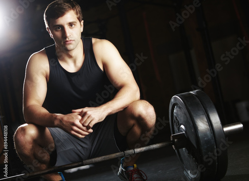 Man, portrait and barbell in gym for fitness with mission or challenge for workout and muscle development. Athlete, face and strong mindset with iron weights for exercise, health and wellness goals