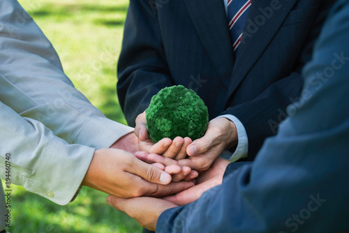 Business people are holding hands around a green globe for ESG, co2, and net zero Concept. Sustainable environment development. World Earth Day and Climate change.