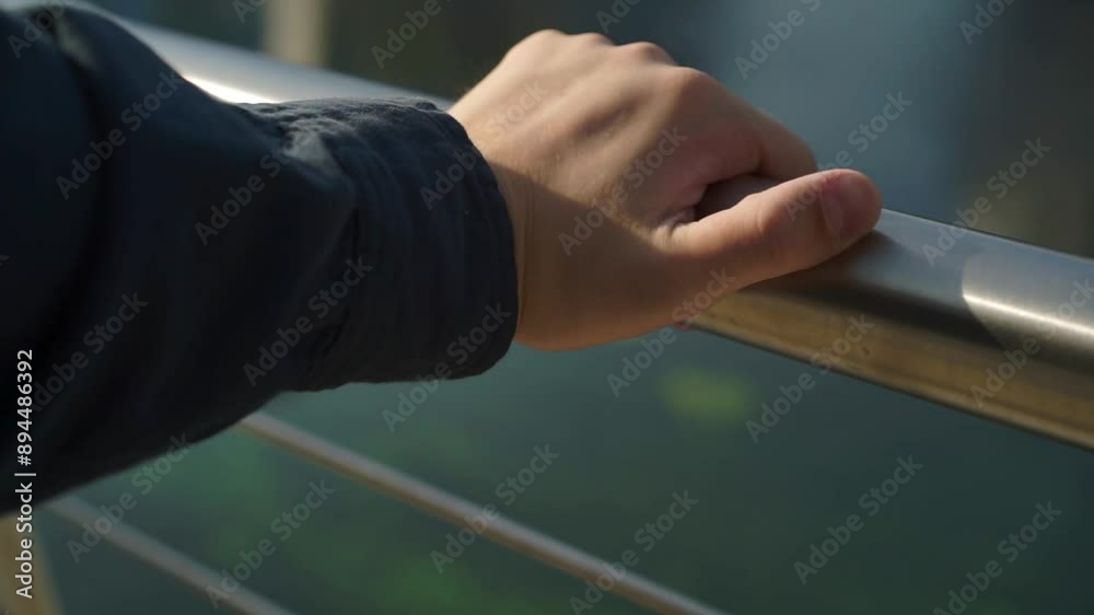 A man stands in a park by a lake, his hands show signs of mental illness, he fidgets nervously, itches and clenches his fists. A man stands in a park by a lake, his hands show signs of mental illness, he fidgets nervously, itches and clenches his fists.