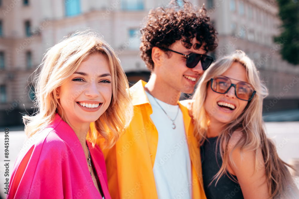 Group of young three stylish friends posing in the street. Fashion man and two cute female dressed in casual summer clothes. Smiling models having fun. Cheerful women and guy outdoors Group of young three stylish friends posing in the street. Fashion man and two cute female dressed in casual summer clothes. Smiling models having fun. Cheerful women and guy outdoors