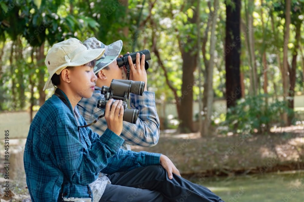 Asian children using binoculars to do the birdwatching in tropical forest during summer camp, idea for learning creatures, wildlife animals and insects outside the classroom. Asian children using binoculars to do the birdwatching in tropical forest during summer camp, idea for learning creatures, wildlife animals and insects outside the classroom.