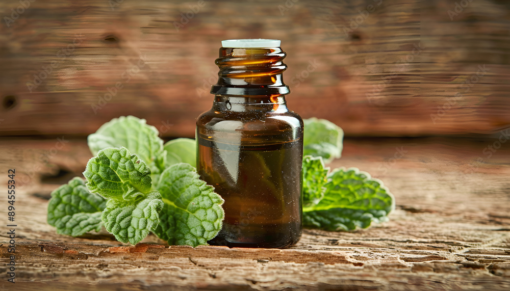 Essential oil of peppermint in a small brown bottle with fresh green mint, rustic style, vintage wooden background Essential oil of peppermint in a small brown bottle with fresh green mint, rustic style, vintage wooden background