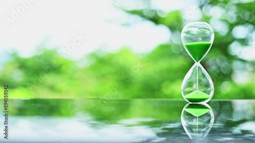 Time lapse of glass hourglass on green nature background
