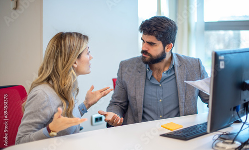 Angry businessman arguing with businesswoman about paperwork failure at workplace.