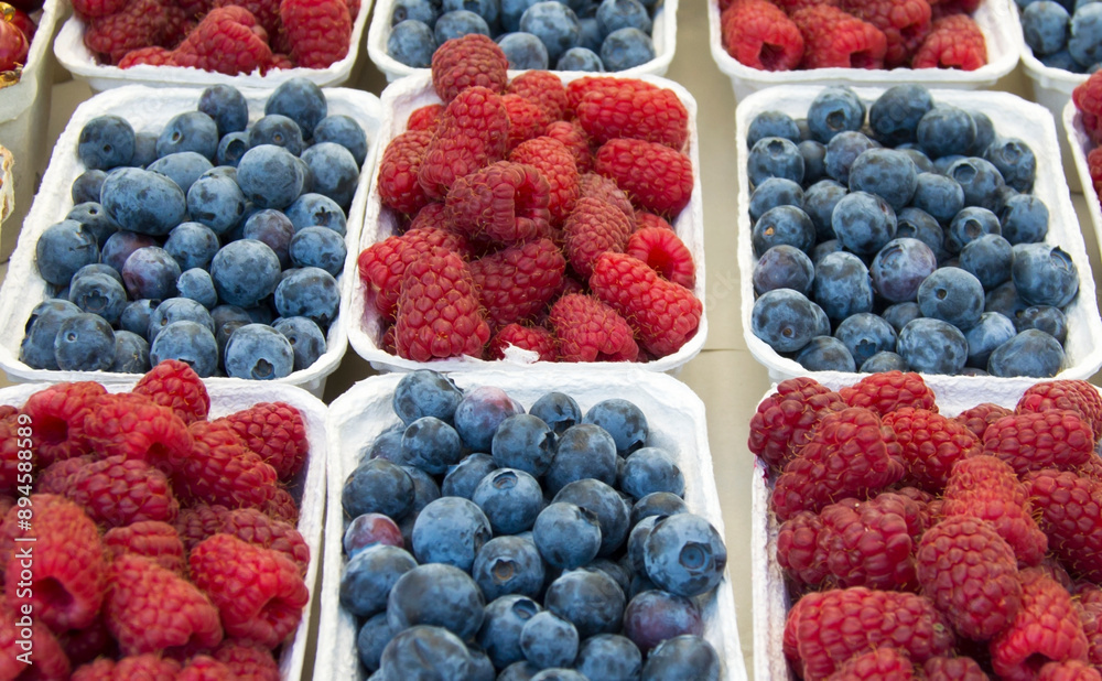 Small paper boxes with blueberries and raspberries displayed on street food market, closeup. Small paper boxes with blueberries and raspberries displayed on street food market, closeup.