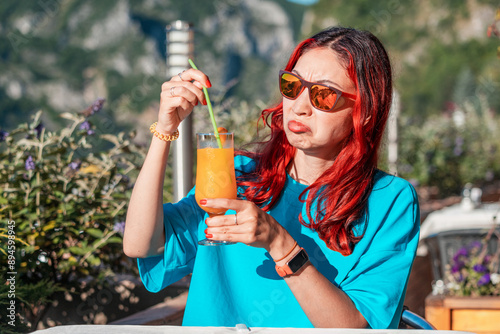 Obraz na płótnie A woman with a disgusted expression, reacting to a spoiled orange juice, highlighting the unpleasant taste and smell of the beverage. w salonie
