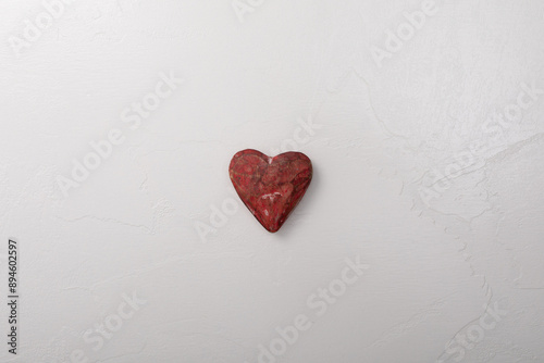 A red heart rests on a whit...