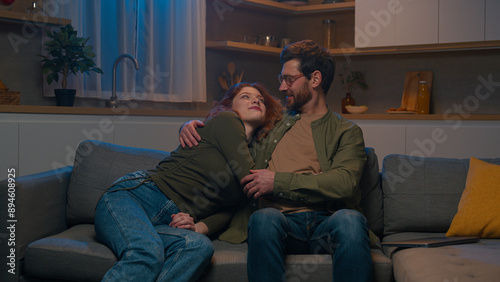Caucasian couple in love man woman husband wife relax together on couch in evening home hugging cuddling enjoying romantic date feel tender affection laughing bonding cuddle hug embrace happy family