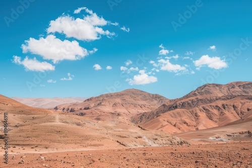 Vast and endless desert mountains under a blue sky with white clouds © F