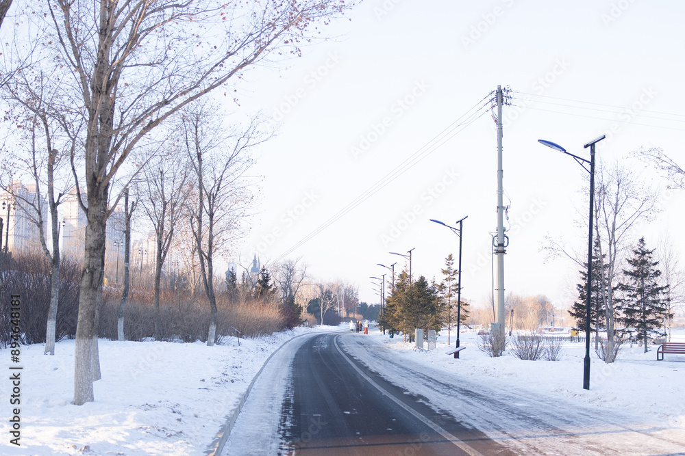 Harbin, China - January 10th, 2024: The small road leading to Harbin city square, snow covered both sides of the road.