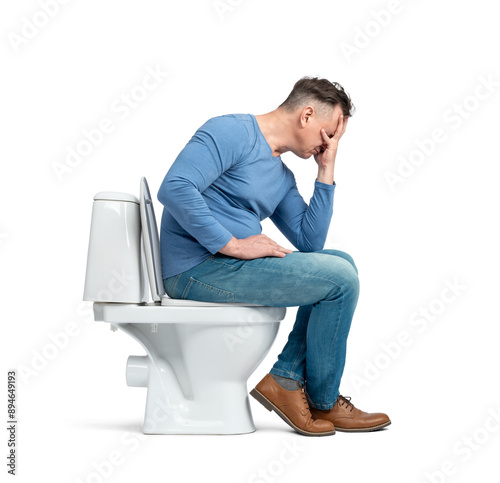 A dressed man sits on the toilet, cupping his face with his palm, facepalming. Side view. Isolated on a transparent background png