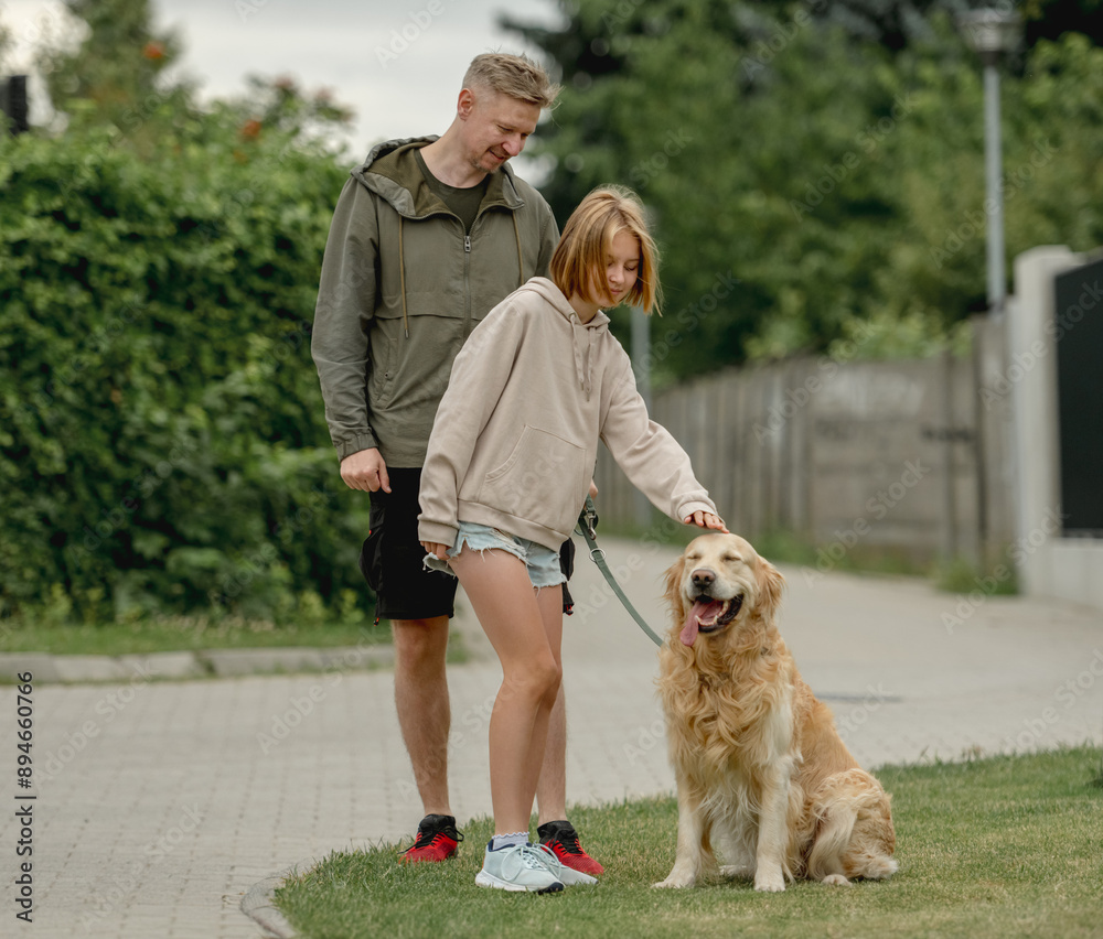 Dad And Daughter Play With Their Golden Retriever Dog During A Walk Dad And Daughter Play With Their Golden Retriever Dog During A Walk