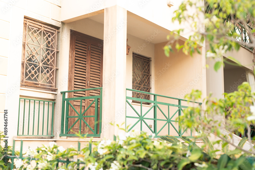 A cream colored building with a green railing and wooden shutters A cream colored building with a green railing and wooden shutters