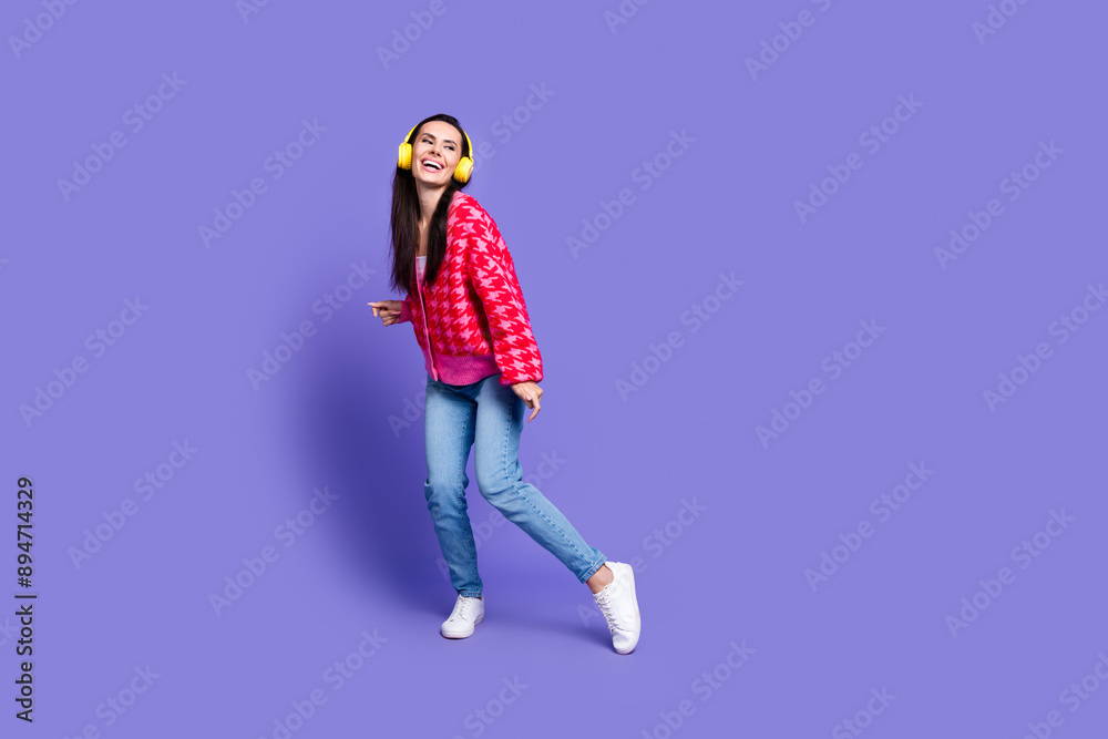 Full length photo of charming positive woman wear pink cardigan headphones dancing empty space isolated purple color background Full length photo of charming positive woman wear pink cardigan headphones dancing empty space isolated purple color background
