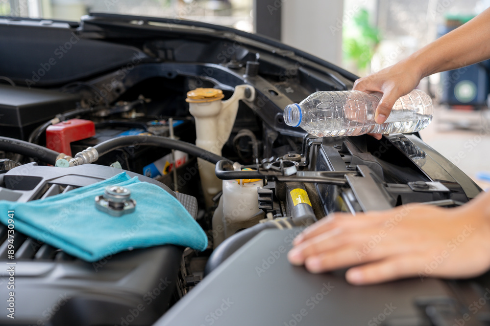 A young woman is filling the car's radiator with water, conducting a vehicle maintenance check A young woman is filling the car's radiator with water, conducting a vehicle maintenance check