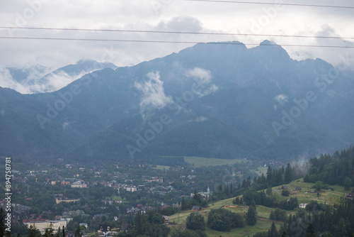 Mountain range. Wildlife in the mountains. White clouds over the peaks of rocky mountains. High mountain peaks. Tatra Mountains. There is a city in the gorge. A settlement at the foot of the mountain.