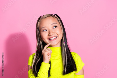 Photo of clever cute girl with dyed hairstyle dressed yellow turtleneck look at offer empty space isolated on pink color background