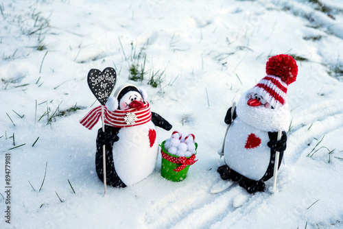 Winter composition: two toy penguins in knitted hats and scarves met on a walk. 
