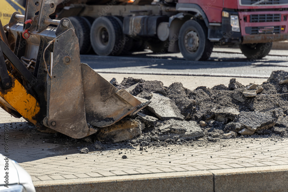A large truck is pulling a large yellow bucket with a hole in the bottom A large truck is pulling a large yellow bucket with a hole in the bottom