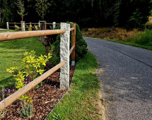 rural fencing made of hewn stove posts style enclosure in the mountains. a bed mulched with bark and perennial blue flowers along the edge photo