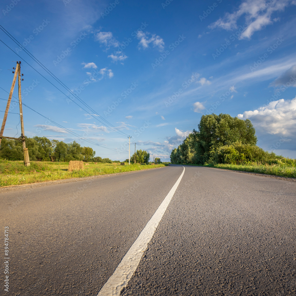 Fototapeta premium A road with a white line down the middle and trees in the background