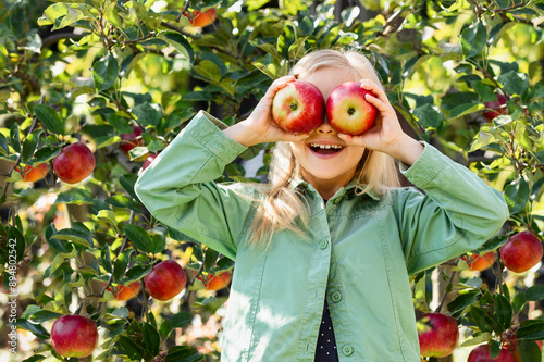 Apples for Children. Happy Little Girl Child with Apple Eyes Having Fun in Apple Orchard. Organic Red Apples for Kids.