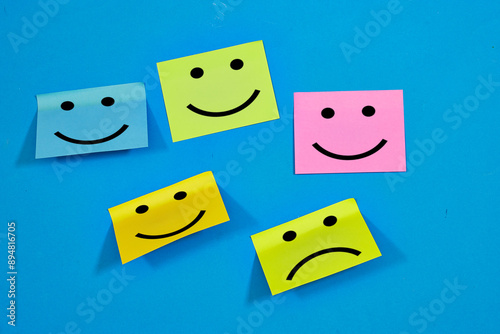 Testimonial rating concept with emotion faces on colorful sticky notes on blue background. happy and sad faces drew on sticky notes