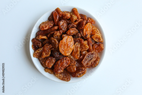 Raisins in small white plate, isolated on white background