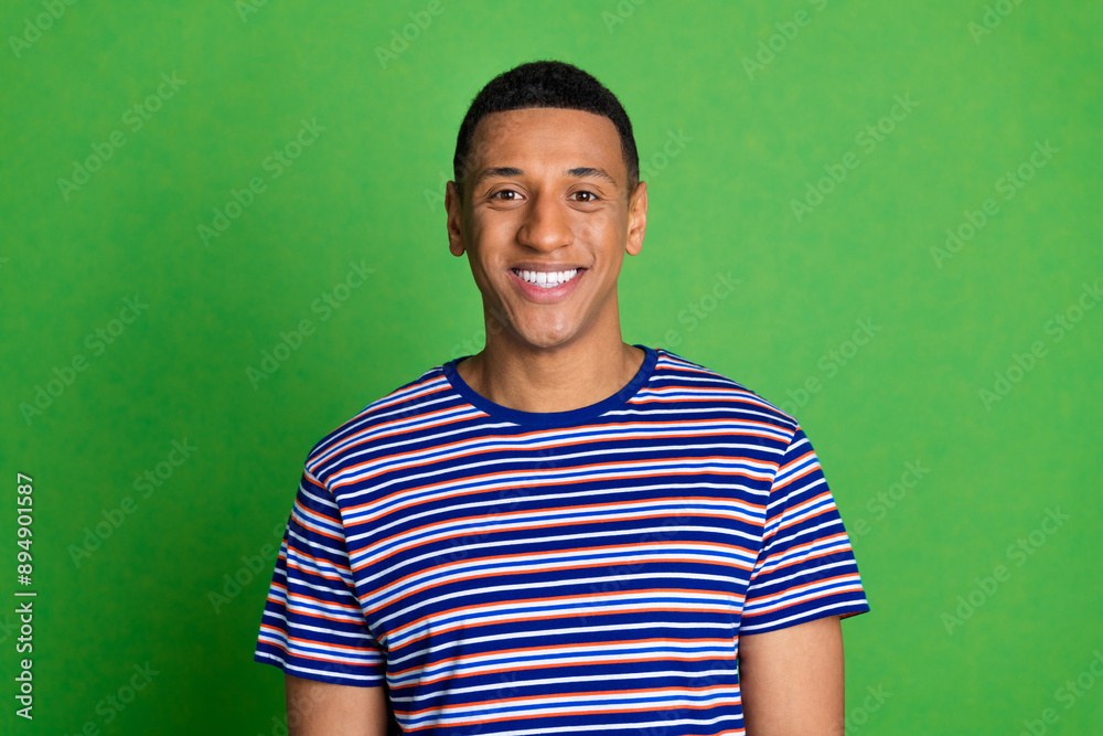 Photo of positive nice man wear striped stylish clothes isolated on green color background Photo of positive nice man wear striped stylish clothes isolated on green color background