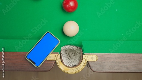 Wallpaper Mural Top view shot of russian billiard green cloth table with smartphone blue screen workspace mockup and white balls being hit by the red ball, advertising space. Torontodigital.ca