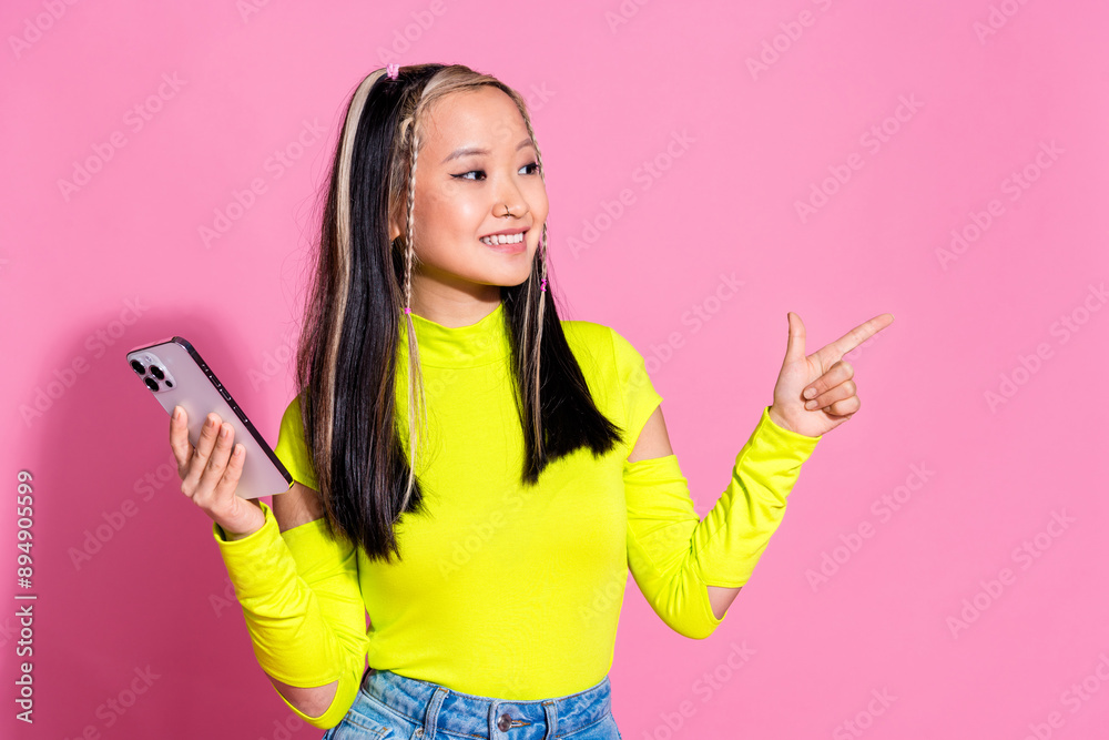 Photo of smart pretty girld ressed yellow shirt hold smartphone look directing at sale empty space isolated on pink color background Photo of smart pretty girld ressed yellow shirt hold smartphone look directing at sale empty space isolated on pink color background