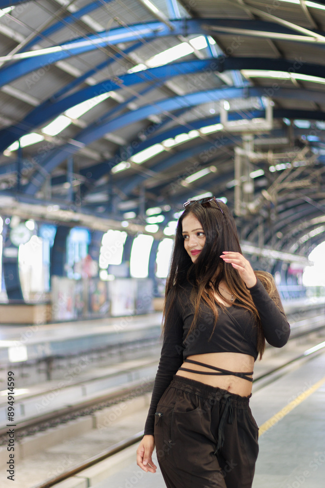Fototapeta premium Young woman standing on a metro station platform and waiting for a metro train. People travel in public transport concept.