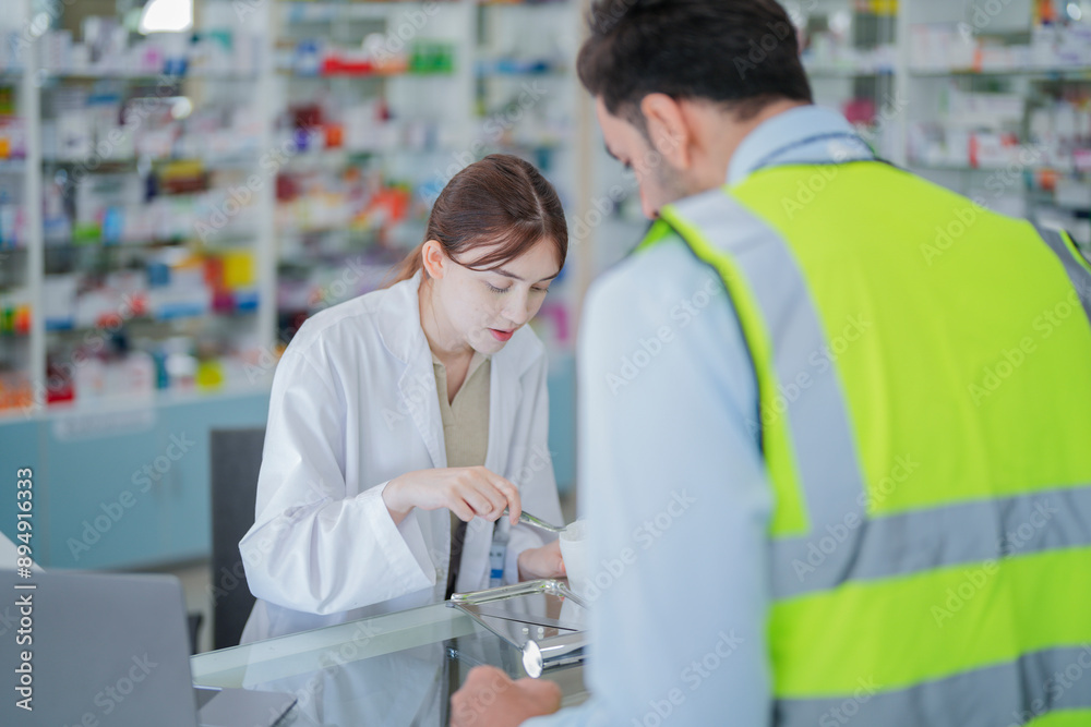 Obraz premium A female pharmacist is talking with a construction worker who needs medicine for pain and discomfort. Pharmacist in a pharmacy with medicines on shelves