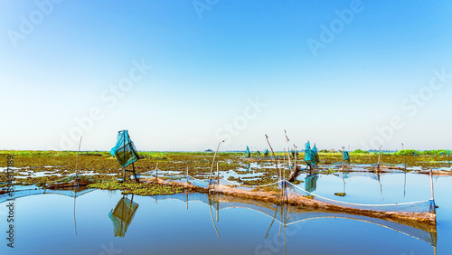 Traditional fish trap with beautiful landscape view. Shrimp and crab traps. Fish trapping on river. Nature fishery background. Dip catcher fishing net homemade of blue nylon nets and steel frame.