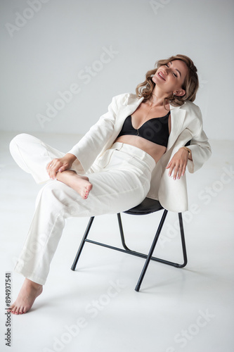 young blonde woman in white jacket and bra on grey background