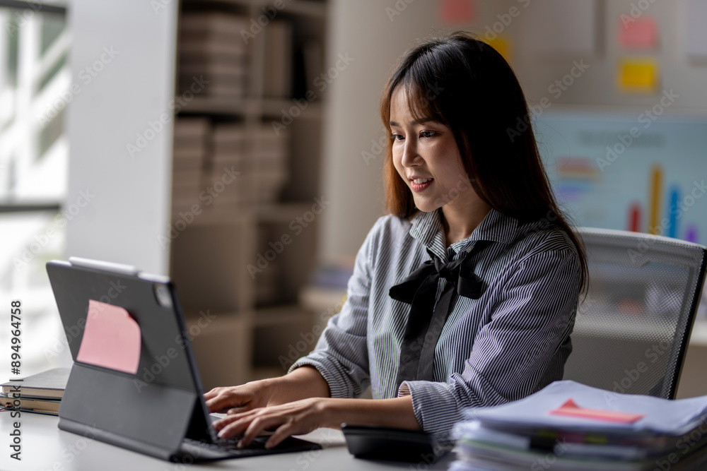 A woman is sitting at a desk with a laptop and a calculator A woman is sitting at a desk with a laptop and a calculator