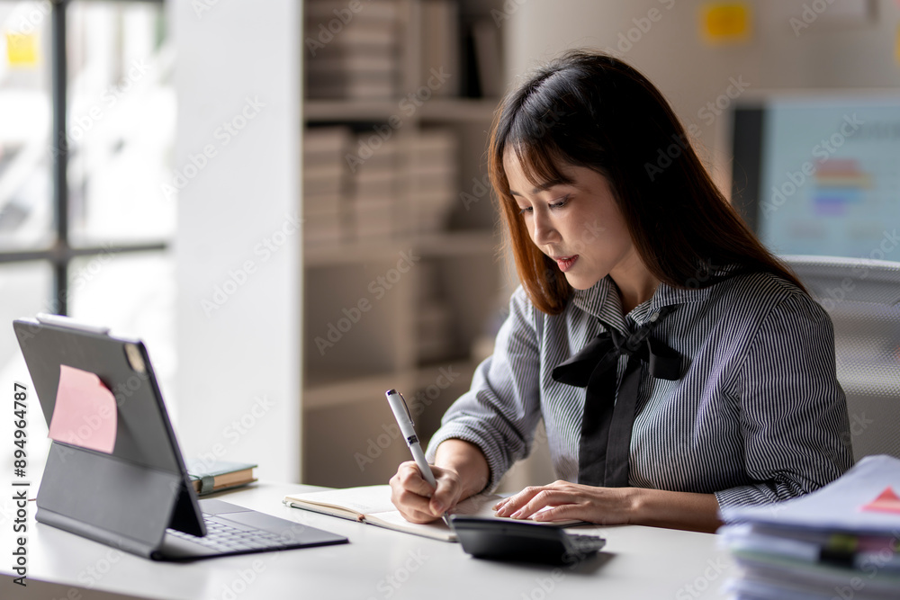 A woman is sitting at a desk with a laptop and a notebook A woman is sitting at a desk with a laptop and a notebook