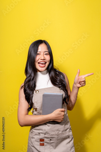 A woman is holding a tablet and pointing to the right