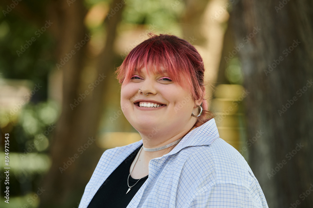 A beautiful woman with pink hair smiles brightly while standing outdoors. A beautiful woman with pink hair smiles brightly while standing outdoors.