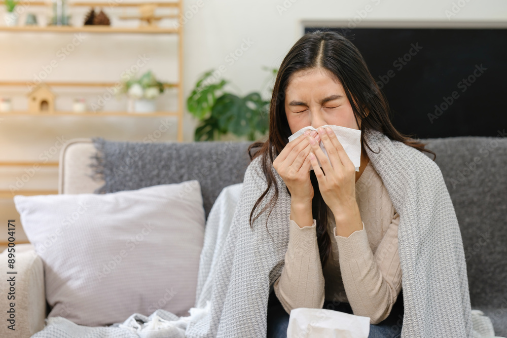 A woman is sitting on a couch with a tissue in her hand, covering her mouth A woman is sitting on a couch with a tissue in her hand, covering her mouth