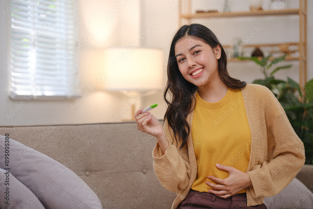 A woman is sitting on a couch with a green pen in her hand