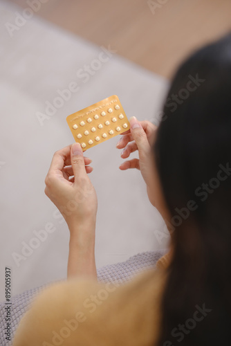 A woman is holding a pack of birth control pills
